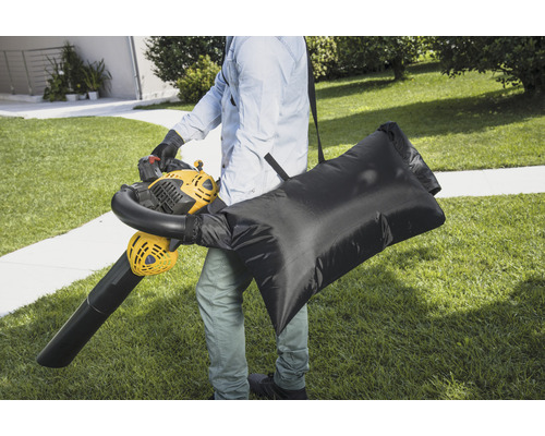 Person med lövblås och uppsamlingssäck i trädgården