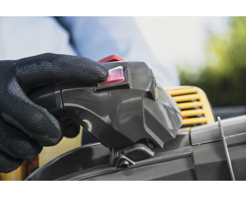 Hand med skyddshandske aktiverar strömbrytare på en lövblåsare