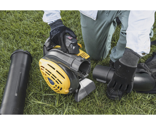 En person monterar en gulgrå lövsug på en gräsmatta.