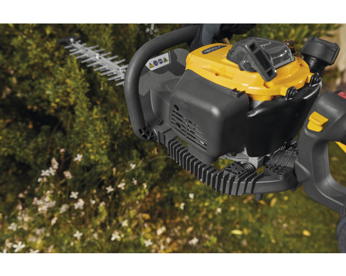 Motordriven häcksax framför växter