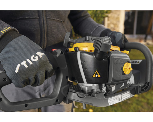 Närbild av en person med Stiga-handskar som håller en häcksax.