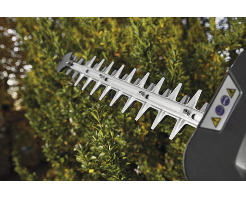 Skärmekanism för en häcksax i drift framför en häck.