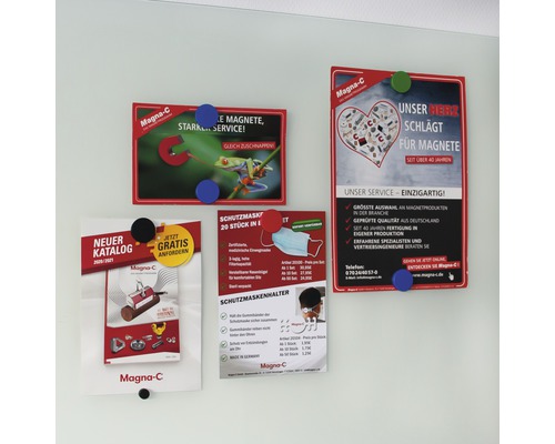 På en vägg hänger fyra reklambroschyrer med magneter från märket Magna-C. De marknadsför magneter, skyddsmasker och kataloger.