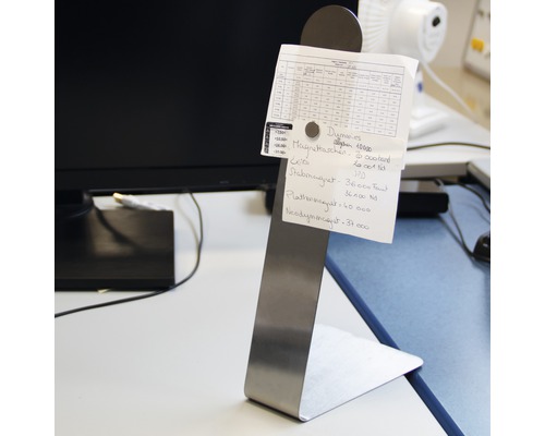 Anteckningshållare i rostfritt stål med anteckningar på ett skrivbord