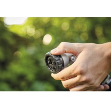 Hand håller trädgårdsslangsprutmunstycke