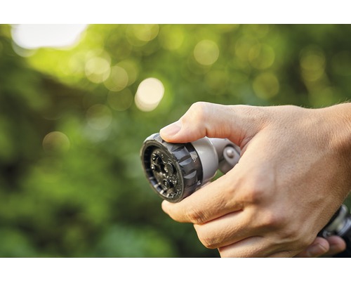 Hand håller trädgårdsslangsprutmunstycke