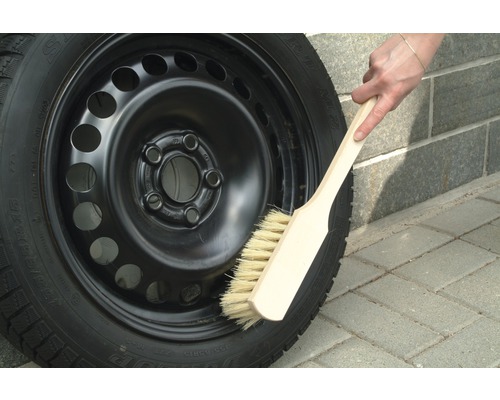 Stålfälg med vinterdäck rengörs med en borste.