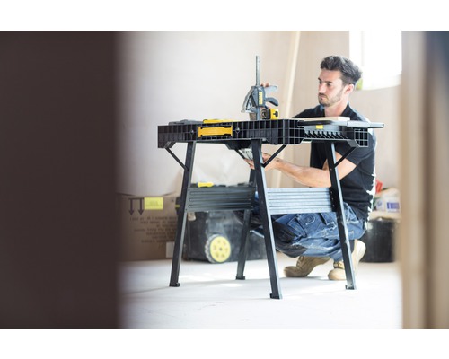 Hantverkare som arbetar på en arbetsbänk med en klämma i ett ljust rum.