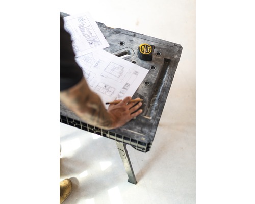 Byggnadsarbetare med ritning, blyertspenna och måttband på en arbetsbänk