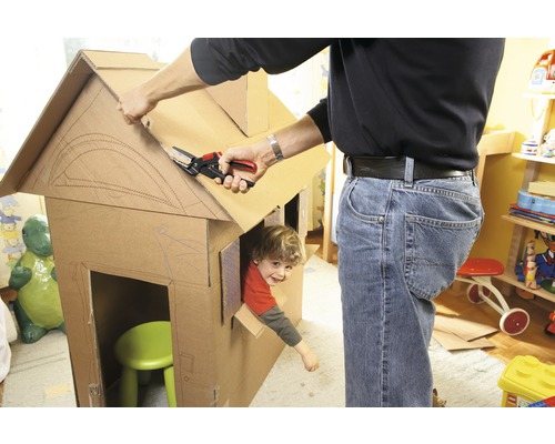 Man som klipper kartonghus med barn med sax