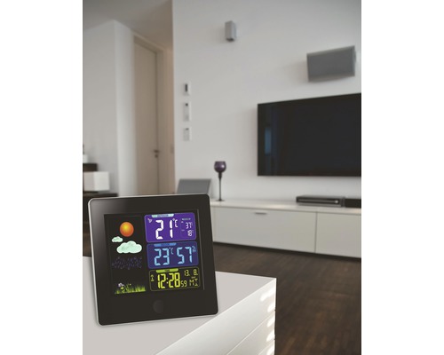 Väderstation med visning av temperatur, luftfuktighet och tid i ett modernt vardagsrum