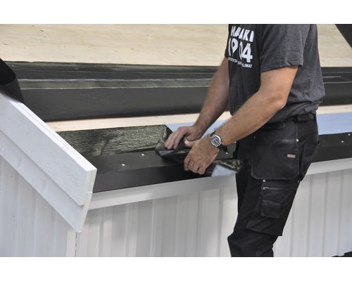 En hantverkare lägger takpapp på ett tak.