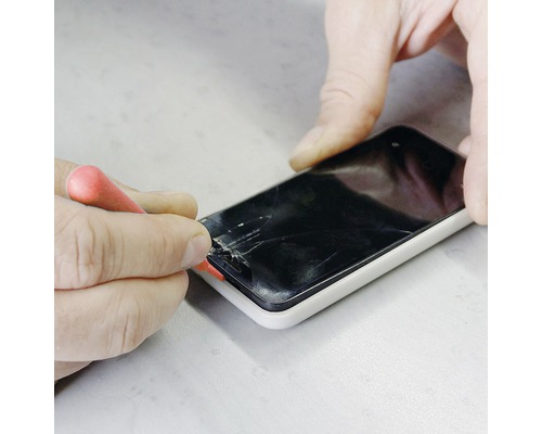 Person som reparerar en smartphone med en skruvmejsel.