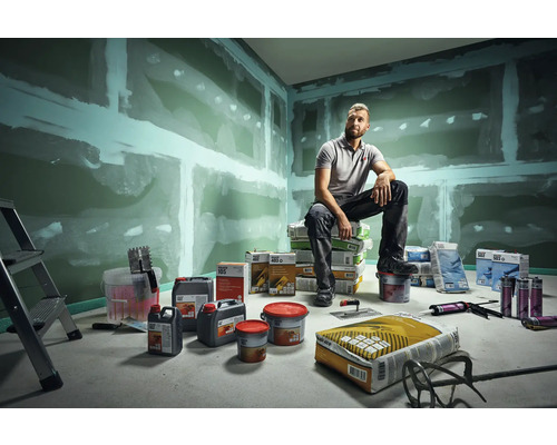 Rum med spacklade gipsskivor, verktyg, spackel och en man som sitter på säckar