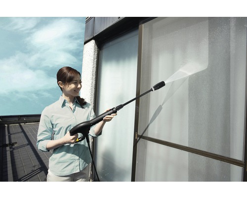 Kvinna rengör fönster med en högtryckstvätt