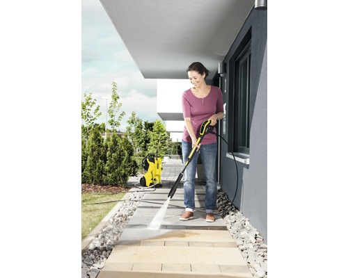 Kvinna rengör trottoarplattor med en Kärcher högtryckstvätt