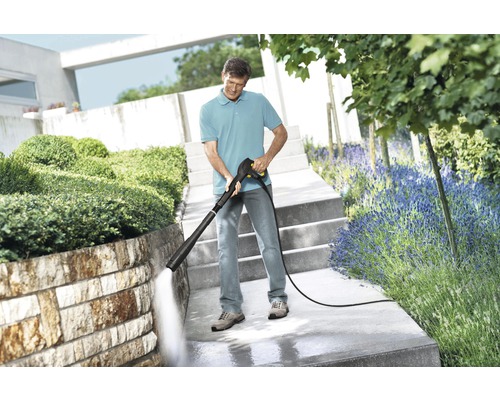 Man rengör en stentrappa i trädgården med en högtryckstvätt.