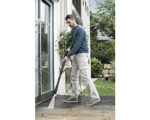 En man rengör en terrass med en högtryckstvätt.