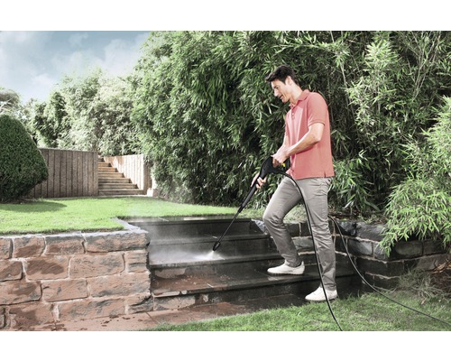 Man rengör utomhustrappa med högtryckstvätt i trädgården.