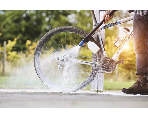 En person rengör en cykel med en högtryckstvätt.