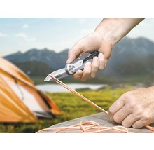 Person skär rep med en fickkniv i naturen.