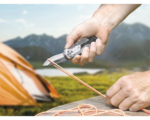 Person skär rep med en fickkniv i naturen.