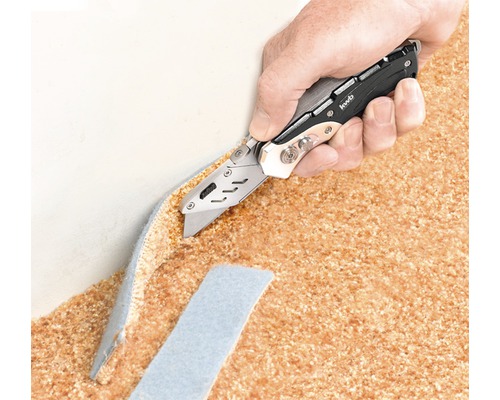 En hand skär en matta med en universalkniv