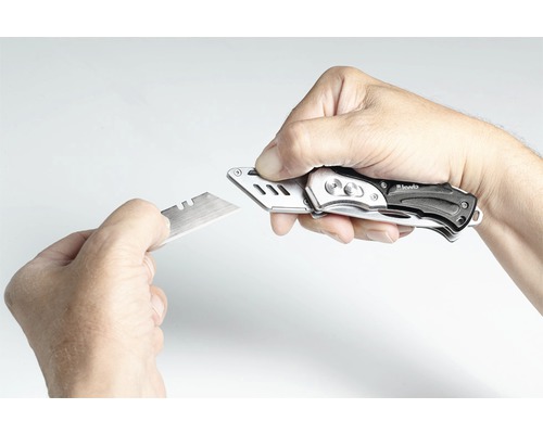 En hand byter bladet på en brytbladskniv