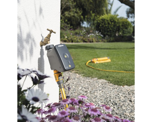Automatisk vattning med en vattentimer på kranen i trädgården.