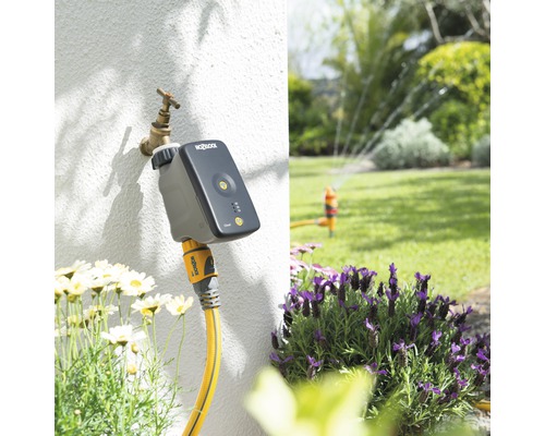 Trädgårdsbevattningssystem med timer och sprinkler i trädgården