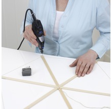 En person borrar en trämodell med ett Dremel multifunktionsverktyg.