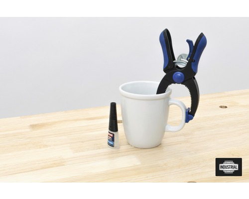 Scen med en fjäderklämma, en mugg och lim på ett bord