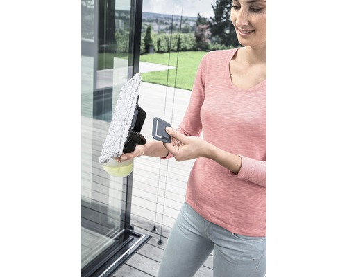 En kvinna rengör en glasruta med en fönstertvätt.