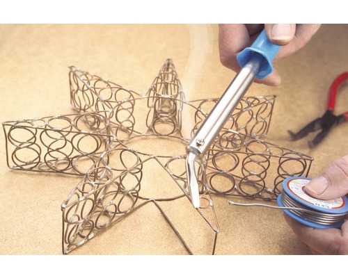 Lödarbete på en metallstjärna med lödkolv och lödtråd.