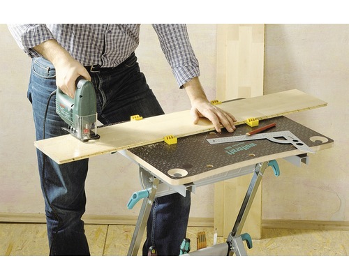 En person sågar en träskiva med en sticksåg på en arbetsbänk.