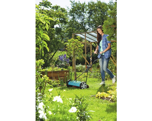 Kvinna använder handgräsklippare i trädgården