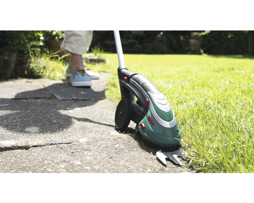 Batteridriven grässax med teleskopskaft på gräsmatta