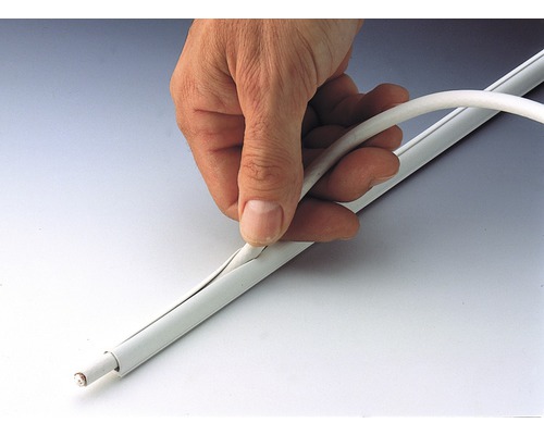 En hand leder en kabel in i en kabelskyddskanal.