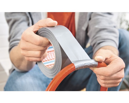 Person reparerar en slang med vävtejp