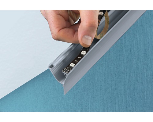 Hand fäster LED-remsa i en profil för indirekt belysning.