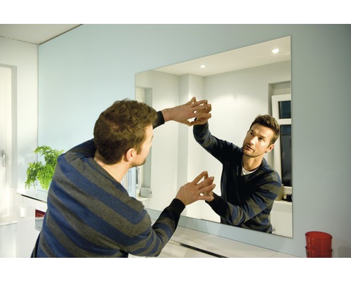 Man monterar en rektangulär spegel i badrummet.