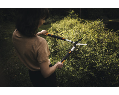 Kvinna klipper häck med en häcksax