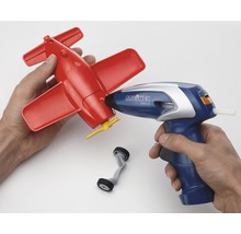 Person använder limpistol för att reparera en röd leksaksflygplan
