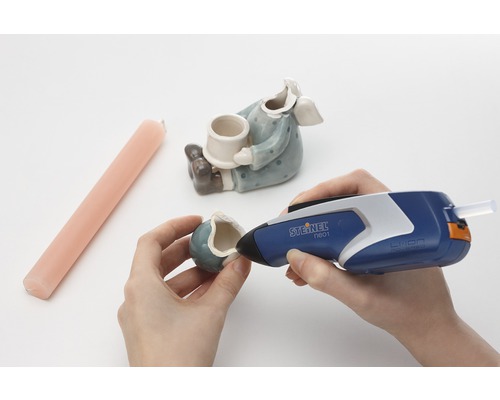 Person reparerar en keramikfigur med en limpistol från Steinel.