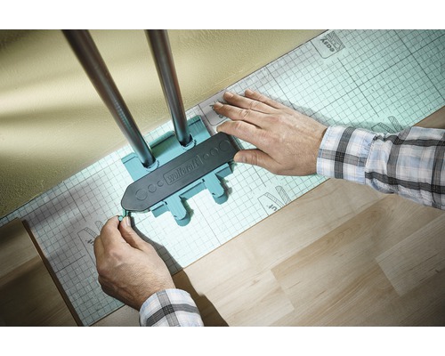 Wolfcraft Logo. En person använder en markör för att markera värmerör på ett isolerande underlag.