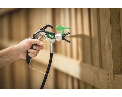 Färgsprutpistol i användning framför trästaket