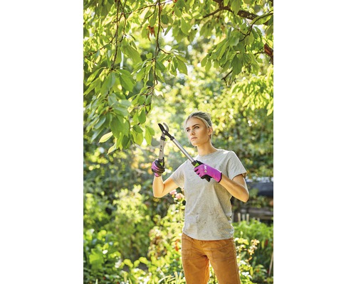 Kvinna beskär grenar med en grensax i trädgården