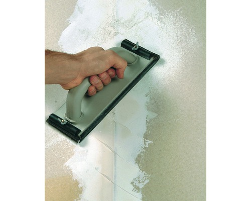 Hand med rivbräda som putsar en vägg