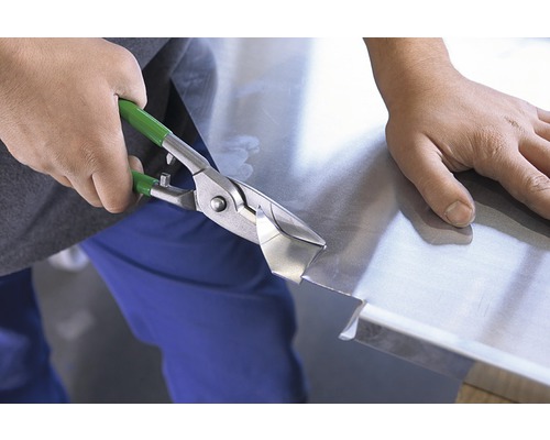 En person klipper plåt med en plåtsax.