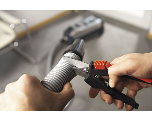 En person skär en dammsugarslang med en slangskärare.